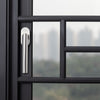 Moderner Edelstahl Fenstergriff an einem schwarzen Metallrahmenfenster mit Stadtblick. Elegantes und langlebiges Design für stilvolle Fensterlösungen.