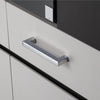 Ein glänzender Möbelgriff an einer Schublade eines weißen Schrankes montiert